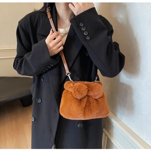 Detail einer karamellbraunen Plüschtasche mit Schleife und Leder-Schultergurt