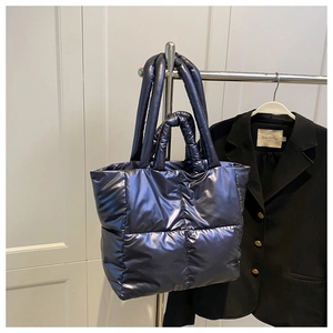 Detail of metallic quilted down tote bag with dual handles hanging on a silver hanger