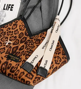 Dettaglio della borsa tote leopardata con tracolle con lettere e targhetta moda