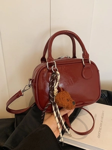 Chic dark red faux leather mini square bag with cute plush puppy charm on black surface