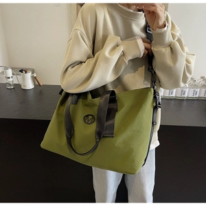 Olive green canvas travel tote with black nylon straps and metal M logo detail