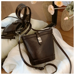 Detailed view of dark brown textured leather bucket bag with silver twist lock and strap
