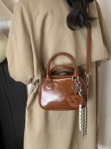 Brown glossy PU leather shoulder bag with a teddy bear charm and woven straps
