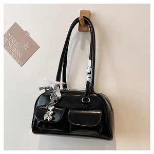 Detail einer glänzenden schwarzen Lackledertasche mit silbernem Herz und Schleife