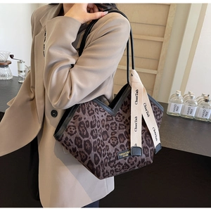 Dettaglio della borsa tote leopardata con bordi in pelle nera e tracolla in tessuto beige