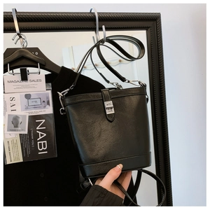 Detail of black bucket bag featuring glossy leather finish and silver twist lock closure