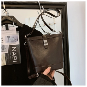Detail view of dark coffee vintage bucket bag with silver twist lock and smooth leather finish
