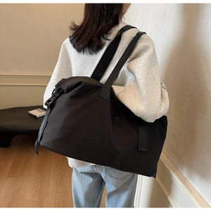 Detail of waterproof travel duffel bag with black shoulder straps and side M logo