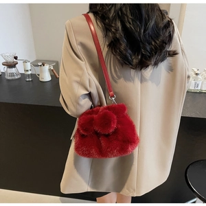 Detail einer roten Pelz-Eimertasche mit Pompons und verstellbarem Leder-Schultergurt