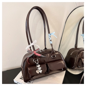 Detailansicht der dunkelbraunen Ölleder-Handtasche mit Vintage-Schleifen und Anhängern