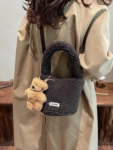 Deep grey plush faux fur bucket bag with bear charm worn by model in beige trench coat