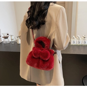 Dunkelrote Plüsch-Eimertasche mit Schleife als Umhängetasche auf khakifarbenem Blazer