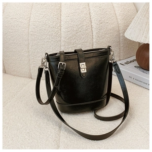 Close-up of a black bucket bag with silver hardware on a soft cream sofa