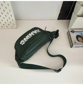 Detail of dark green nylon chest bag with silver JANING print and zipper layers