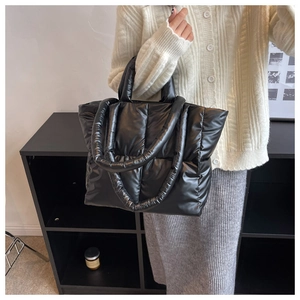 Close-up of quilted black puffer tote bag with glossy finish and soft padded handles