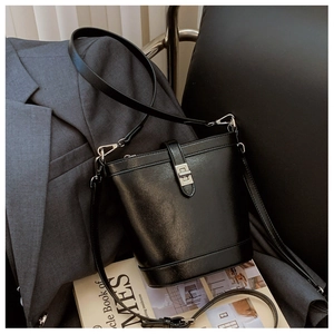 Detail of the silver metal clasp and fine grain leather texture on the black bucket bag