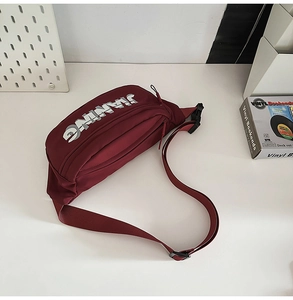Detail of burgundy nylon chest bag with JIANING logo and durable black plastic buckle