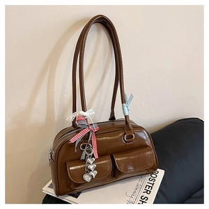 Nahaufnahme der braunen glänzenden Bowling-Tasche mit Spitzenschleife und Herzanhängern