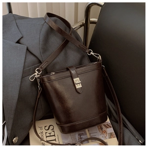Detail of dark brown bucket bag with shiny leather texture and silver metallic buckle