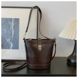 Detail of dark brown bucket bag featuring a silver twist lock and smooth leather finish