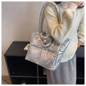 Silver quilted puffer tote bag detail with padded handles and shiny metallic finish