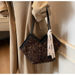 Dettaglio della borsa tote leopardata con finiture in pelle nera e nastro decorativo