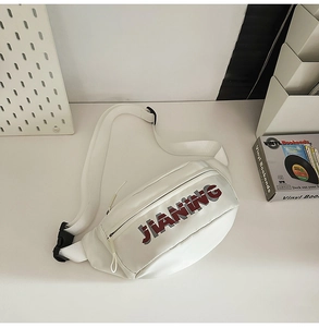 Close-up of white crossbody bag with JIANING logo and black buckle detail