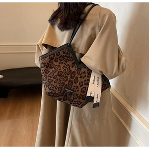 Dettaglio della borsa tote leopardata con manici in pelle nera e nastro decorativo