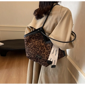 Dettaglio della borsa tote leopardata con finiture in pelle nera e nastro decorativo