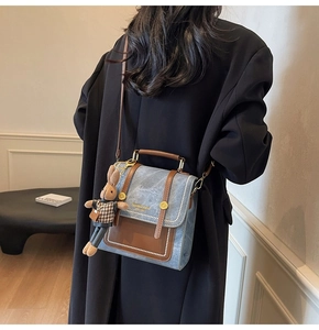 Blue crossbody bag with brown trim and rabbit charm shown on model from behind