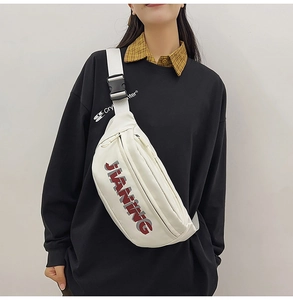 Detailed view of white crossbody chest bag with JIANING letter print on model wearing black hoodie