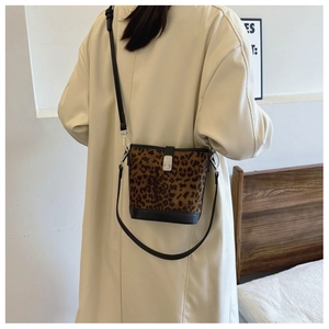 Detail of leopard print bucket bag with black leather strap on a model shoulder