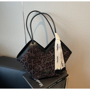 Dettaglio della borsa shopper leopardata con foulard di seta su divano nero