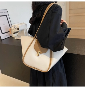 Détail d'un grand sac cabas bicolore crème et beige porté par un mannequin au café