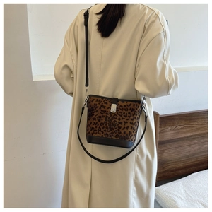 Detailed view of the leopard print bucket bag with black leather strap on a model
