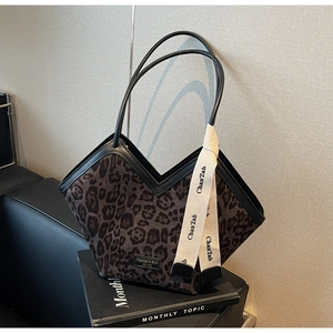 Dettaglio della borsa tote leopardata con manici in pelle nera e nastro in tela