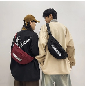 Detail view of black and burgundy cross-body chest bags with white lettering and adjustable straps