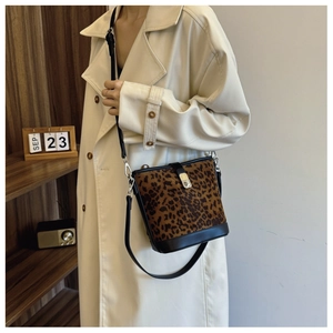 Detail of leopard print bucket bag featuring a metal buckle and black leather strap