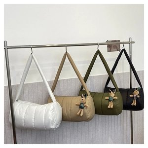 Detailed display of quilted puffer pillow bags in white, khaki, green and black with charms