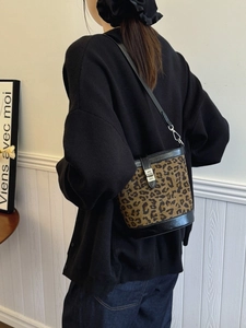 Fashionable leopard print bucket bag with black leather trim and silver metal buckle
