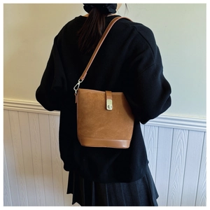 Detail of vintage brown suede bucket bag with leather trim and silver metal twist lock