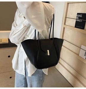 Détail du sac cabas en cuir noir avec boucle dorée verticale et fines bandoulières