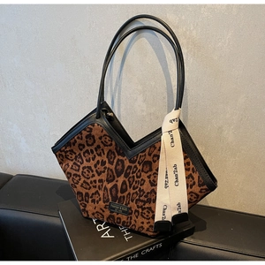 Dettaglio della borsa leopardata con taglio a V e tracolla decorativa con scritte