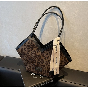 Dettaglio della borsa tote leopardata con manici in pelle nera e nastro decorativo