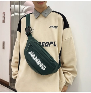 Detail view of the green crossbody bag with adjustable strap and white text logo