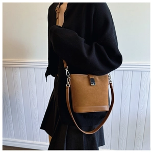 Detailed side view of a vintage brown bucket bag with mixed textures and metal buckle