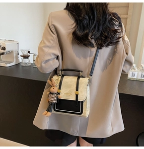Detail of vintage beige and black crossbody bag with rabbit charm in cafe setting