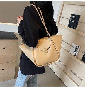 Détail d'un cabas beige avec côtés en forme d'éventail et fermoir métallique doré chic