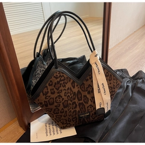 Dettaglio della borsa tote leopardata con taglio a V, manici neri e nastro decorativo