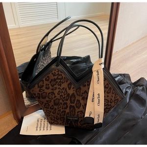 Dettaglio borsa tote leopardata con apertura a V e manici in pelle nera di lusso